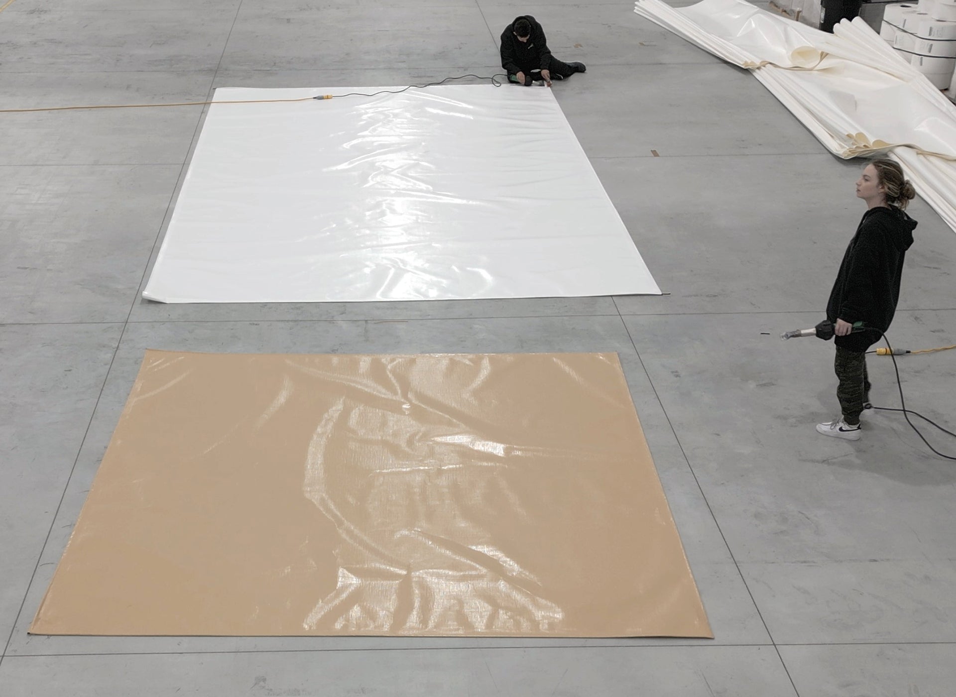Image of employees working on 40x40 White & Beige Tarps in Warehouse-Supreme Tarps